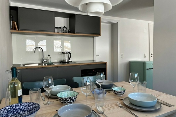 Offene Küche & Esszimmer  Küche und Esszimmer sind offen mit dem Wohnraum verbunden. Die Küche ist komplett ausgestattet und bietet – verteilt auf zwei Küchenzeilen – alles zum gemeinsamen Kochen, Essen und Genießen: Kühlschrank, Herd, Backofen/Mikrowelle