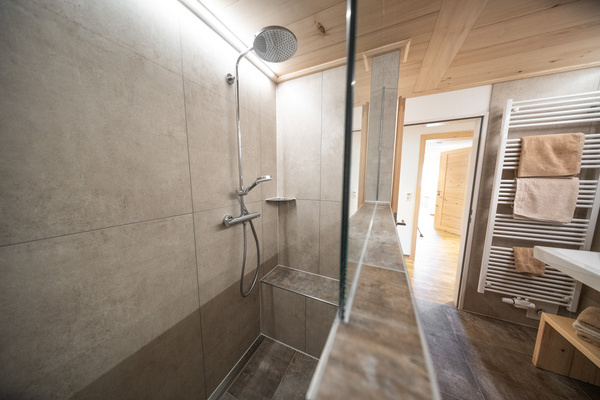 Badezimmer mit Regendusche, Sitzbank in der Dusche, Toilette und Waschmaschine